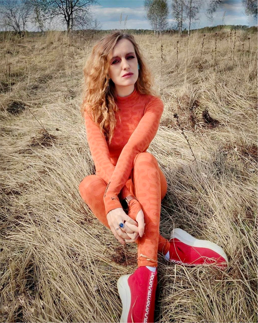 Woman in orange Monosuit sitting in field