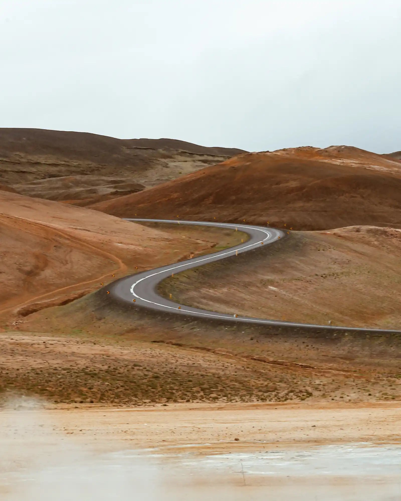 Winding paved road curves through barren desert hills.